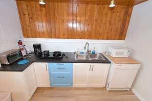 A compact kitchen with a wooden ceiling, a sink, a microwave, a toaster, and a coffee maker.