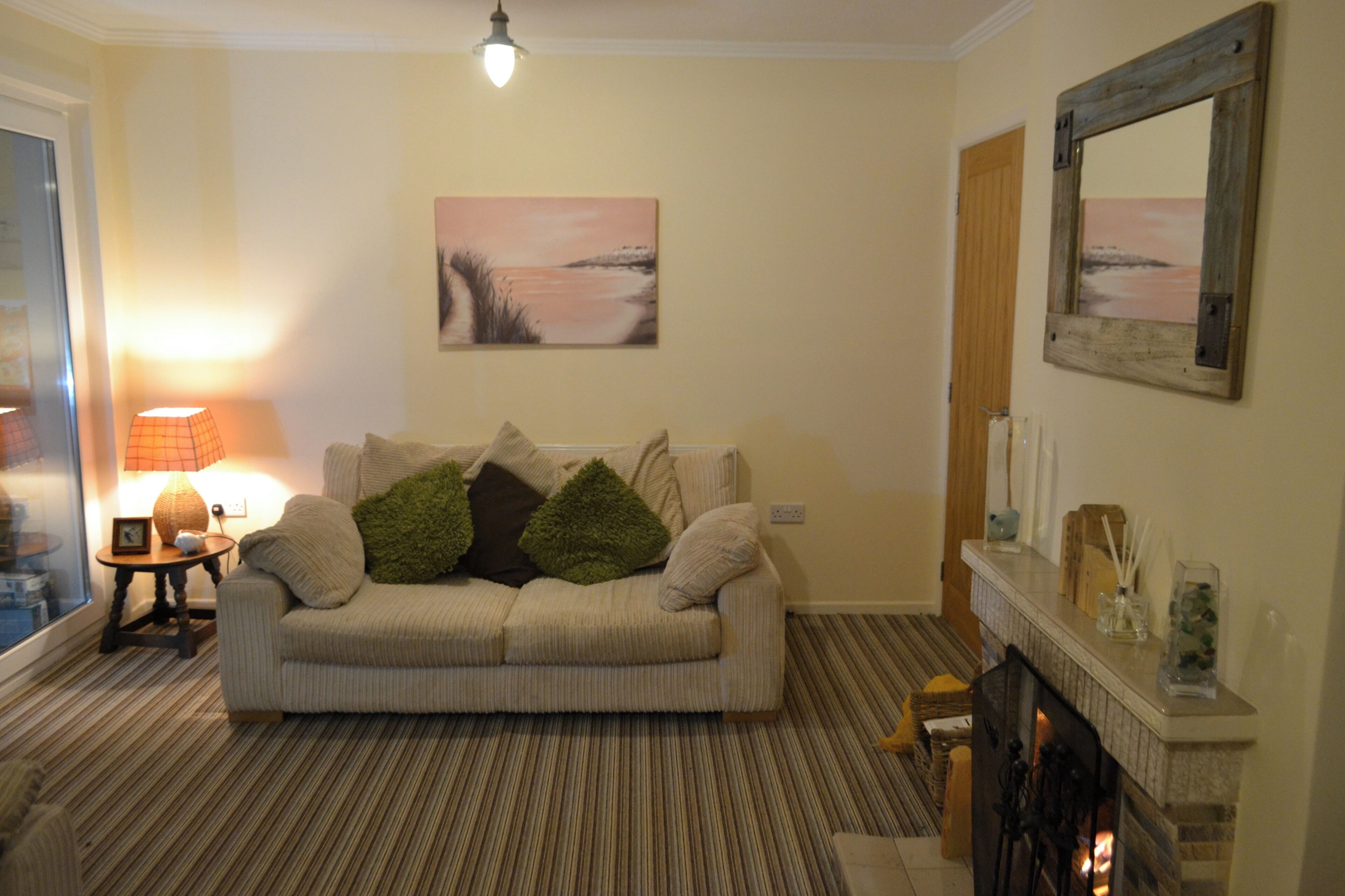 A living room with a sofa, a lamp, a fireplace, and a painting on the wall.