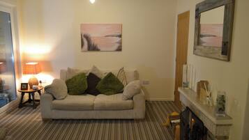 A living room with a sofa, a lamp, a fireplace, and a painting on the wall.