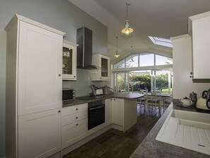 A modern kitchen with white cabinetry, a large window, and a view of the outdoors. - Sea Side - Stay 6 - Petfriendly - Parking - Garden (Rhosneigr)