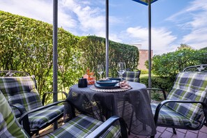 An outdoor patio with a table set for dining, surrounded by chairs.
