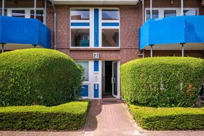 A building with a number '27' on the door, a blue and white window, and a brick facade.