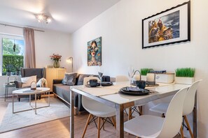 A modern living room with a dining area, a sofa, a coffee table, and a painting on the wall.