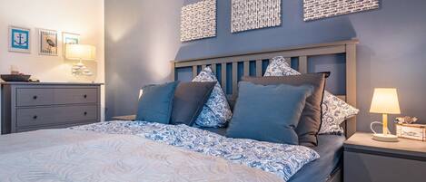 Een slaapkamer met een bed, nachtkastjes en decoratie aan de muur.