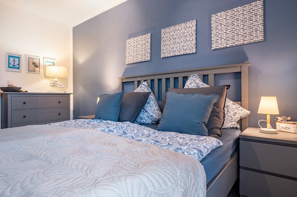 A bedroom with a bed, bedside tables, and wall decor.