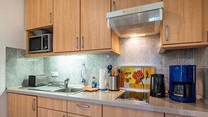 A kitchen with wooden cabinets, a microwave, toaster, coffee maker, and a kettle. - Apartment "Heimathafen" with Private Terrace and Wi-Fi (Wurster Nordseeküste)