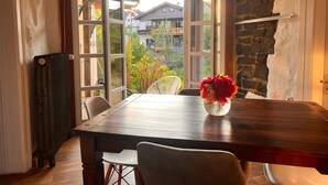An open dining area with a table, chairs, a radiator, and a stone wall. - Apartment 'Schmuckstück' with Garden & Wi-Fi near Cologne, Pet-Friendly (Waldbröl)