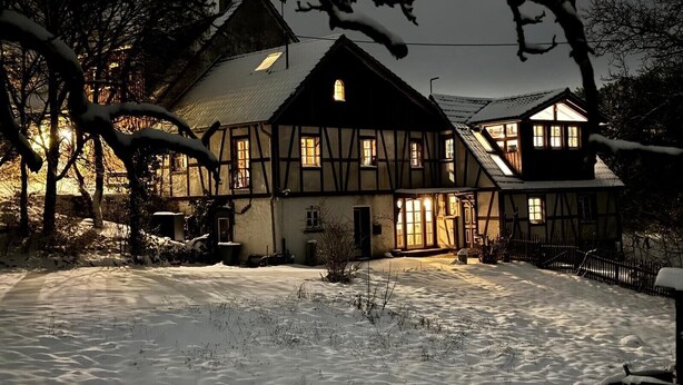 A traditional half-timbered house with a snow-covered yard and illuminated windows. - Apartment 'Schmuckstück' with Garden & Wi-Fi near Cologne, Pet-Friendly (Waldbröl)
