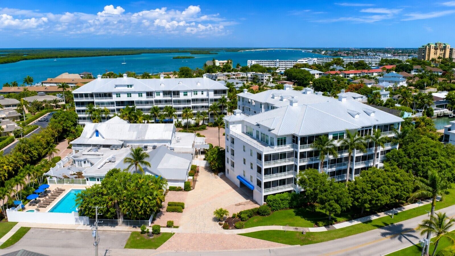 A hotel with multiple buildings, a swimming pool, and a view of the ocean.