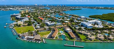 An aerial view of a coastal resort area with a marina, multiple buildings, and a large hotel complex.