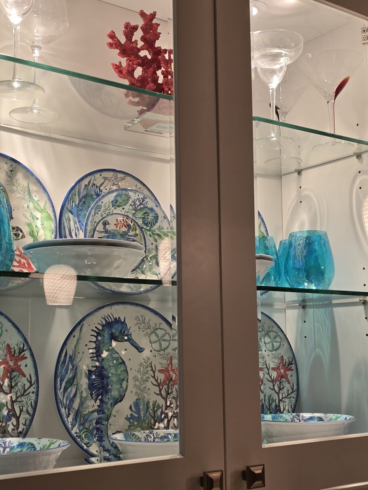 A display of glassware and ceramic plates with marine-themed designs.