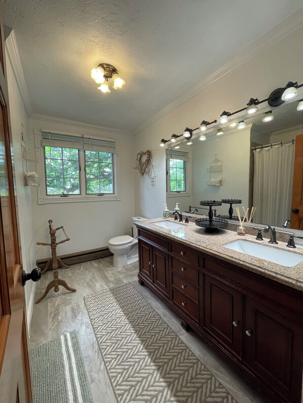 A bathroom with a double vanity, a large mirror, and a ceiling light fixture. - Escape to Montana - Ranch-Style Home with Hot Tub & Mountain Views (Belgrade)