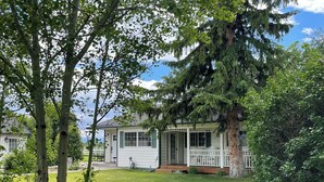 A house with a porch, a lawn, and a large tree. - Escape to Montana - Ranch-Style Home with Hot Tub & Mountain Views (Belgrade)