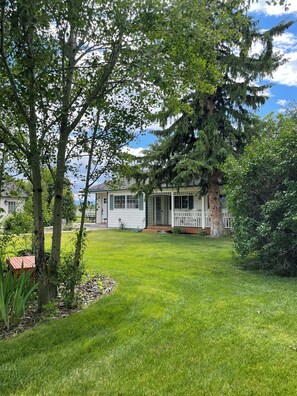 A house with a porch, a lawn, and a large tree.