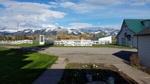 A rural setting with a white building, a fenced area, and a mountain range in the background. - Escape to Montana - Ranch-Style Home with Hot Tub & Mountain Views (Belgrade)