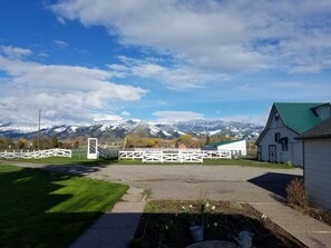 A rural setting with a white building, a fenced area, and a mountain range in the background.