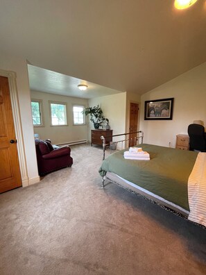 A bedroom with a bed, a dresser, a chair, a window, and a door.