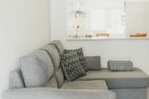 A grey sofa with a zigzag patterned pillow and a grey knitted throw. - Best Houses 15 - Vivenda Adelino Martins (Ferrel)