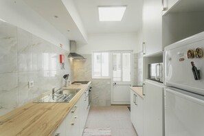 A modern kitchen with white cabinetry, a wooden countertop, and a built-in microwave. - Best Houses 15 - Vivenda Adelino Martins (Ferrel)