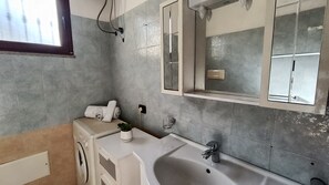 Een badkamer met een bad, een wastafel, een spiegel en een raam.