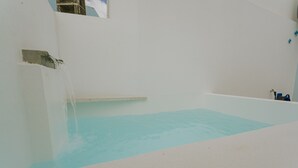 A room with a bathtub filled with water, a window, and a wall-mounted faucet. - Best Houses 17 - Casa da Saudade (Geraldes)