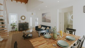A spacious living area with a dining table set, a sofa, and a staircase with plants. - Best Houses 17 - Casa da Saudade (Geraldes)