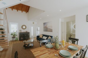 Ein geräumiger Wohnbereich mit Esstisch, einer Couch und einer Treppe mit Pflanzen.