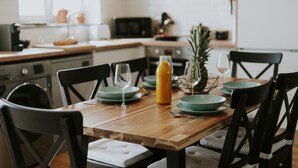 A wooden dining table with chairs, a pineapple, a glass of orange juice, and a bottle of water. - Best Houses 17 - Casa da Saudade (Geraldes)