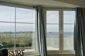 Ein Zimmer mit großem Fenster und Blick auf das Meer und das entfernte Land.