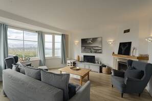 Ein Wohnzimmer mit Sofa, Sesseln, Fernseher, Kamin und Kunstwerken.