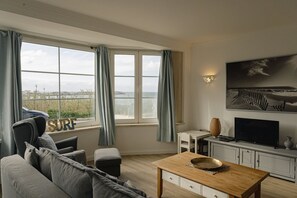 Ein modernes Wohnzimmer mit großem Fenster, Fernseher und einem Gemälde an der Wand.