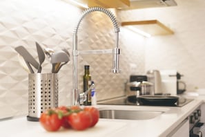Una cocina moderna con un grifo de acero inoxidable, un portalapizcas y un bol de tomates.