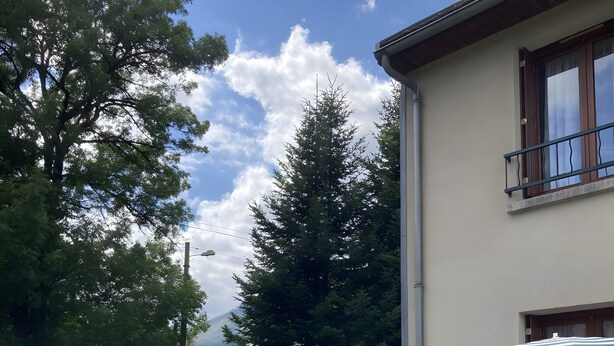 Talo, jossa on patio, pöytä ja tuolit sekä raidallinen aurinkovarjo.