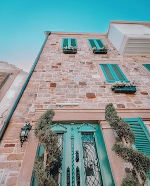 A stone building with green shutters and a central door. - Galinis 1894 Cunda (Ayvalık)