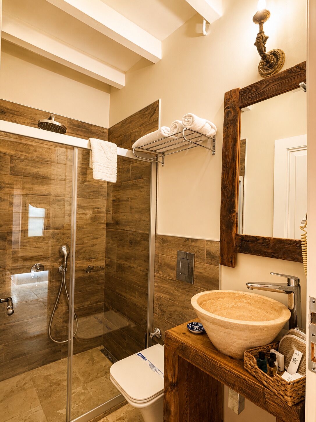 A bathroom with a glass-enclosed shower, a wooden vanity with a large basin, and a mirror with a wooden frame.