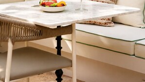 Un comedor con una mesa, un bol de fruta y un vaso de bebida.