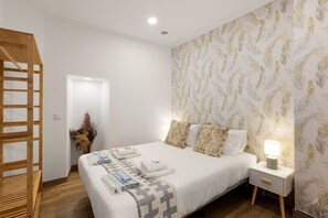 A bedroom with a bed, a nightstand, a lamp, a wooden ladder, and a door. - Best Houses 77 - Best Village I (Peniche)