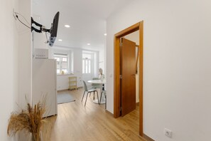 A modern kitchen with a built-in oven, a dining area with a table and chairs, and a wooden door leading to another room. - Best Houses 77 - Best Village I (Peniche)