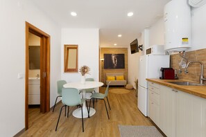 Cocina compacta con comedor, piso de madera y diseño moderno.