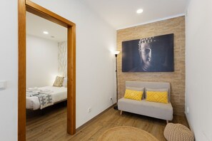 Un dormitorio con una cama, un sofá, un cuadro colgado en la pared y suelo de madera.