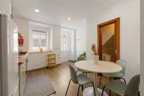 Cocina moderna con refrigerador, un armario de madera, un estante amarillo y una ventana con cortinas.