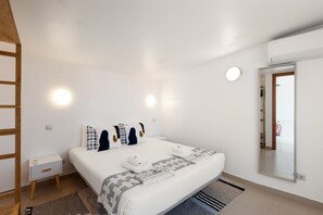 Ein Schlafzimmer mit einem Bett, Nachttischen, einem Spiegel und einer Tür.