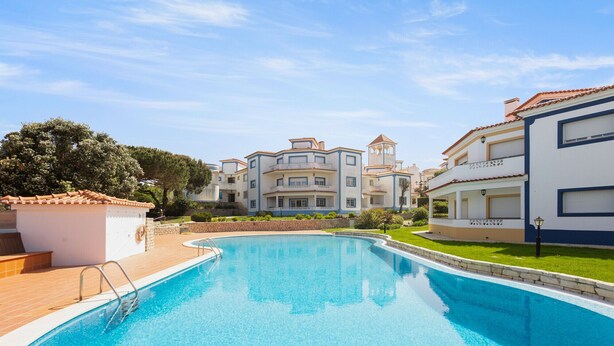 A swimming pool surrounded by buildings with balconies and a clear sky. - Best Houses 91 - Casa D'el Rey (Amoreira)