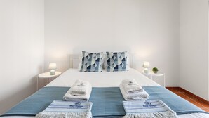 A hotel room with a neatly made bed, two bedside tables with lamps, and a blue and white striped throw blanket. - Best Houses 91 - Casa D'el Rey (Amoreira)