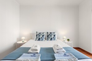 A hotel room with a neatly made bed, two bedside tables with lamps, and a blue and white striped throw blanket. - Best Houses 91 - Casa D'el Rey (Amoreira)