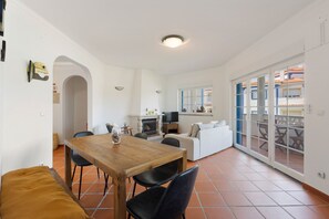 A spacious living area with a wooden dining table, black chairs, a sofa, and a TV. - Best Houses 91 - Casa D'el Rey (Amoreira)