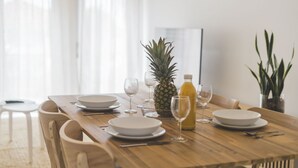 Ein Esstisch gedeckt mit Tellern, Gläsern, einer Ananas und einer Flasche.