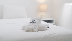 Ein ordentlich bezogenes Bett mit einem gefalteten Handtuch und einem Kopfkissen.