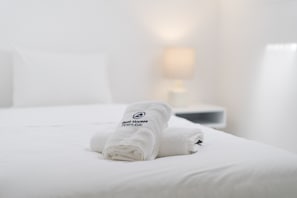 Ein ordentlich bezogenes Bett mit einem gefalteten Handtuch und einem Kopfkissen.