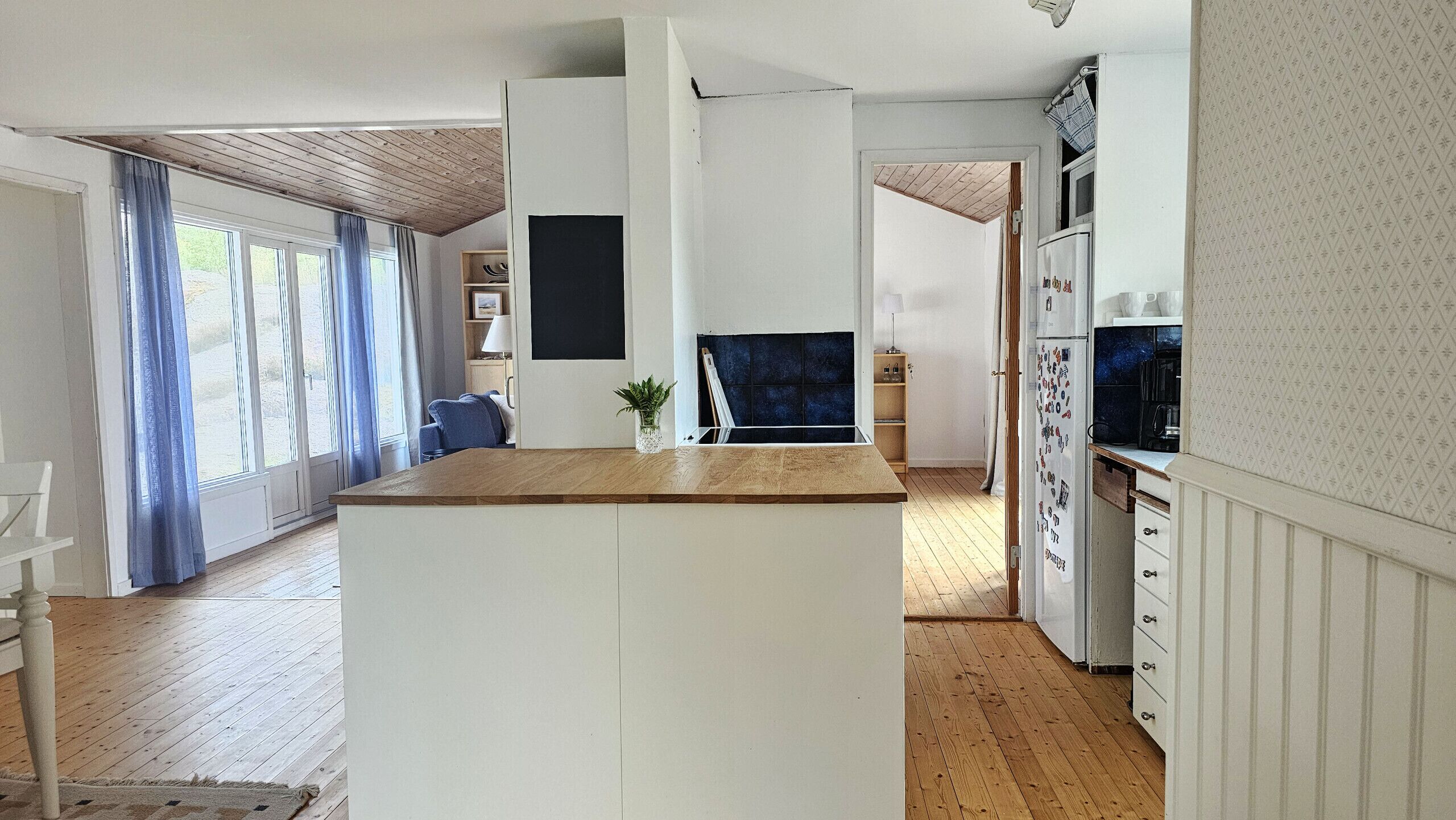 Uma cozinha moderna com piso de madeira, armários brancos e uma ilha central.